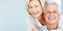 Senior female smiling and embracing senior male partner from behind