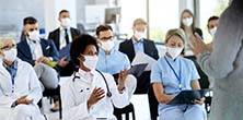 A group of medical professionals sitting in a classroom and interacting with a teacher