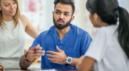 Healthcare workers in a group setting listening to a person in the group speaking